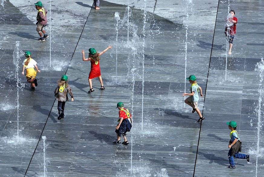 Erstklaessler mit gruenen Muetzen vergnuegen sich am Mittwoch, 11. August 2004 auf dem neugestalteten Bundesplatz in Bern beim Wasserspiel. Die Kinder erhalten im Gebiet des Polizeikonkordats Nordwest ...