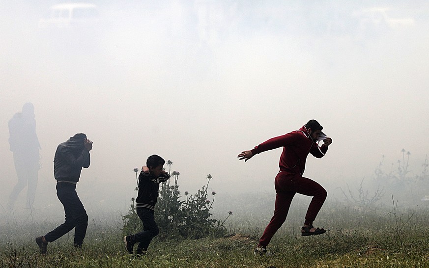 epa06637425 Palestinian protesters run for cover from Israeli tear-gas during clashes after protests along the border between Israel and Gaza Strip, in the eastern Beit Hanun town, in the northern Gaz ...