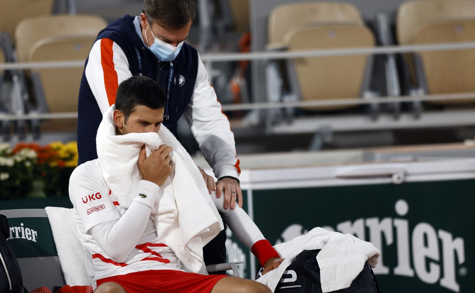 epa08727298 Novak Djokovic of Serbia gets medical assistance during a break as he plays Pablo Carreno Busta of Spain during their men?s quarter final match during the French Open tennis tournament at  ...