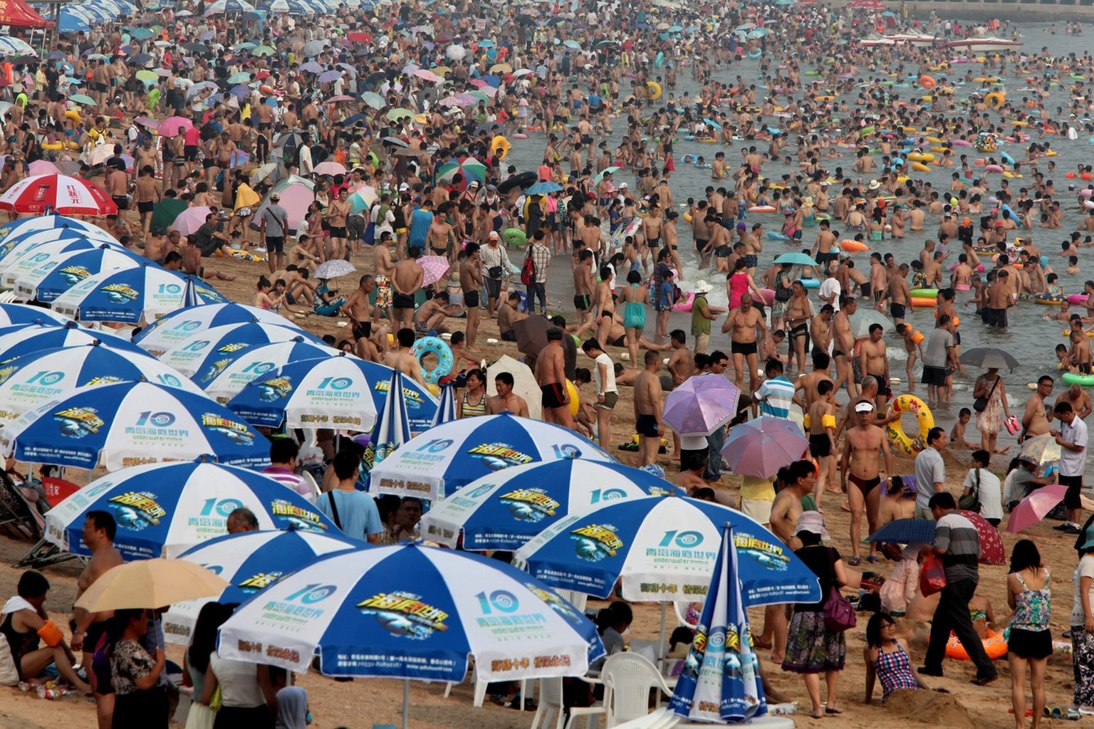 epa03800675 Tens of thousands of locals and tourists pack onto a bathing beach of Huiquan Bay in coastal Qingdao city, eastern China&#039;s Shandong province, 25 July 2013 China&#039;s tourism industr ...