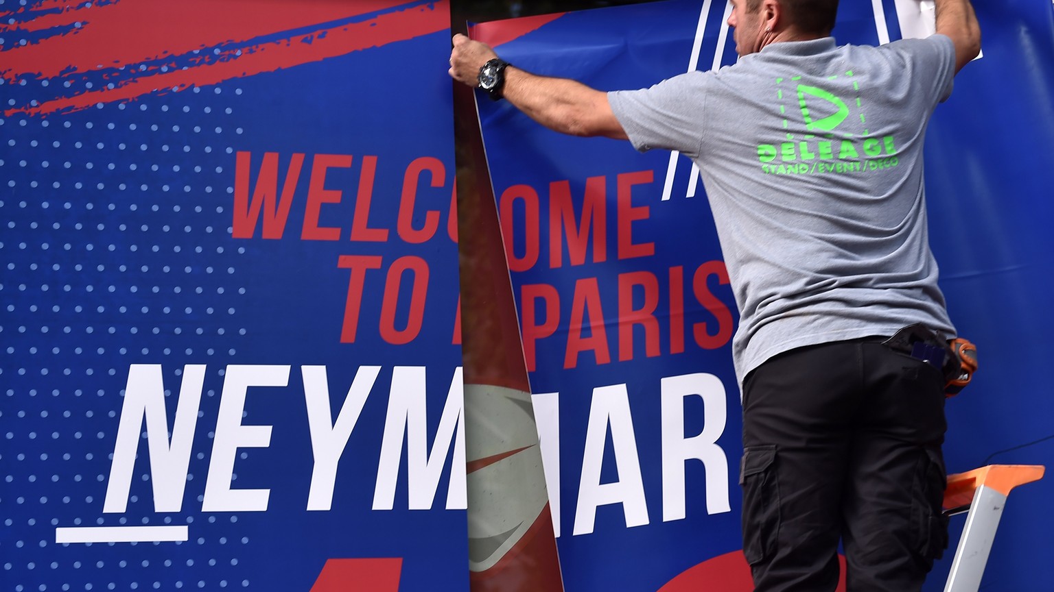 epa06124025 Staff members display a billboard reading &#039;Welcome to Paris Neymar Jr 10&#039; on the facade of the official Paris Saint-Germain (PSG) store on the Champs Elysee avenue in Paris, Fran ...