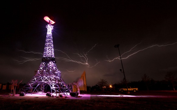 Lightning rips through the night sky Thursday, April 3, 2014 behind a replica Eiffel Tower in Paris, Texas as a severe thunderstorm moved through the Southern part of Lamar County bringing high winds, ...