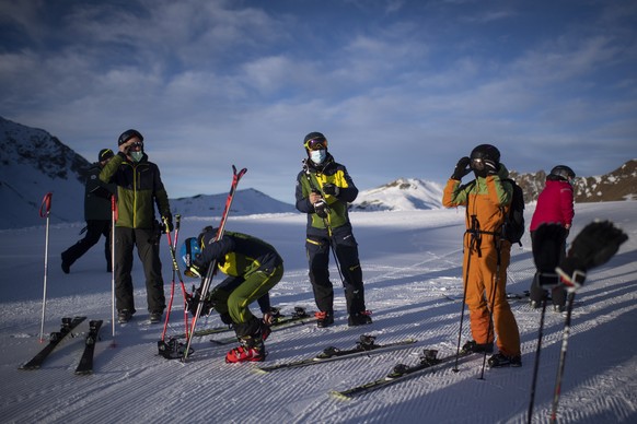 epa08850308 Ski enthusiasts with protective face masks enjoy the day in Arosa, Switzerland, 29 November 2020. Ski resorts in Switzerland are open despite the Covid-19 coronavirus pandemic with strict  ...