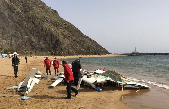 epa05689407 A handout photo made available by Consortium of Firefighters of Tenerife shows Police officers inspect the debris of a light aircraft that made an emergency landing at Las Teresitas beach  ...