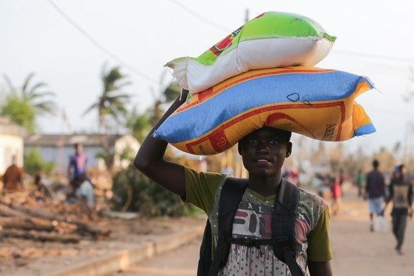 epa07468579 A young boy carries rice after arriving from a boat in the village of Buzi after the passage of cyclone Idai in the province of Sofala, central Mozambique, 28 March 2019. Reports state tha ...