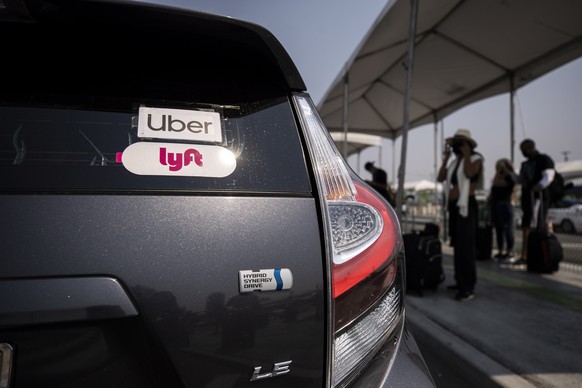 epa08615328 The Uber and Lyft stickers are displayed on a car at LAX Rideshare Lot 1 as Mobile Workers Alliance organizes a rally close by as part of a statewide day of action to demand that both ride ...