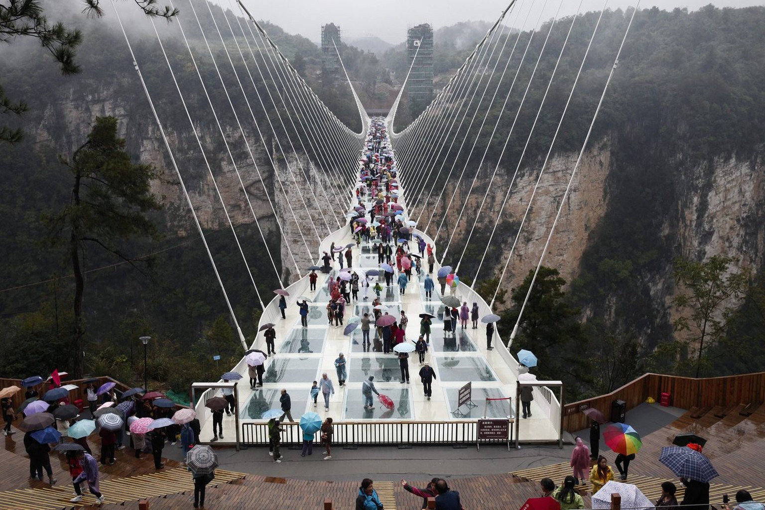 epa05593522 Tourists walk on the Zhangjiajie Grand Canyon Glass Bridge in Zhangjiajie City, Hunan Province, central China, 20 October 2016. Claimed by China to be the longest and highest glass bridge  ...