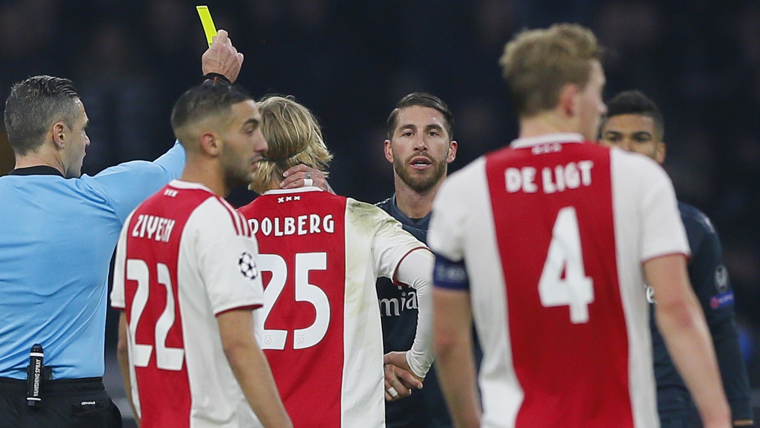 This Wednesday Feb. 13, 2019, image shows referee Damir Skomina, left, showing a yellow card to Real&#039;s Sergio Ramos, center, after a foul on Ajax&#039;s Kasper Dolberg during the first leg, round ...