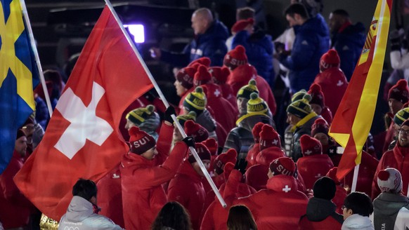 Switzerland&#039;s ski racer and gold and silver medalist Ramon Zenhaeusern walks with the Swiss flag next to team members of Switzerland during the closing ceremony of the XXIII Winter Olympics 2018  ...