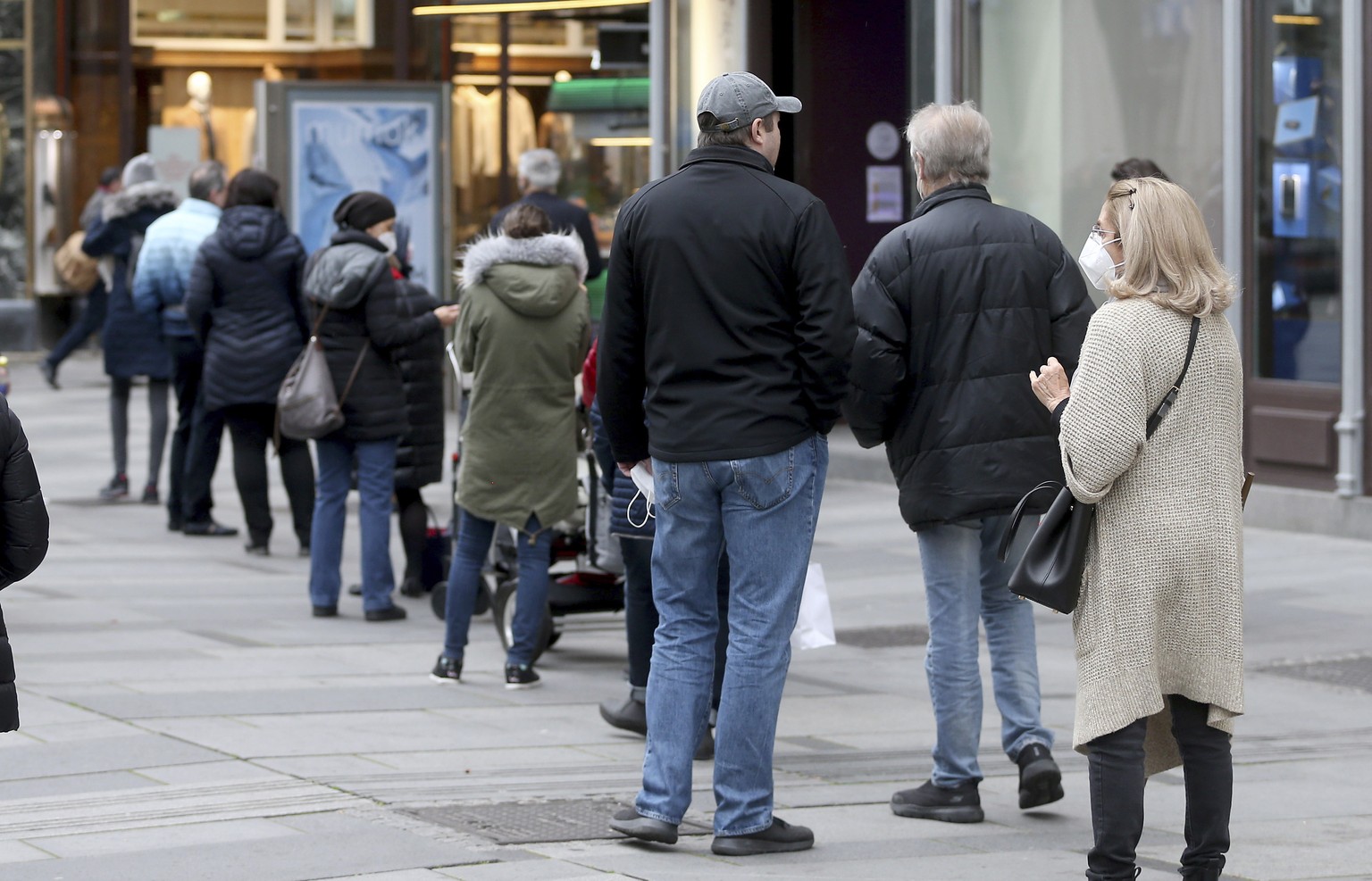 People line up in front of a shop in Vienna, Austria, Monday, Nov. 16, 2020. In an effort to slow the onset of the COVID-19 coronavirus the Austrian government restrict freedom of movement for people  ...