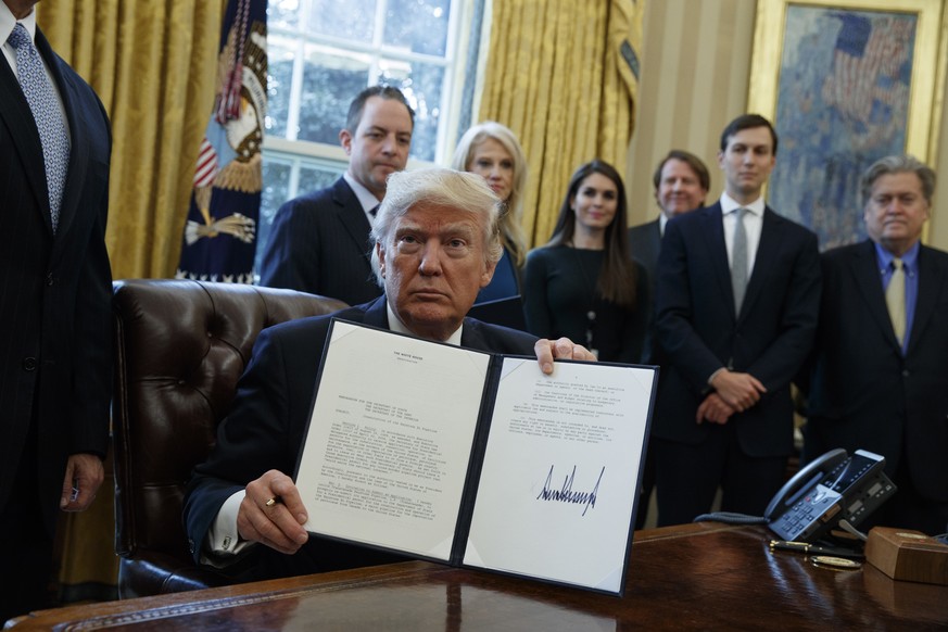 President Donald Trump shows his signature on an executive order on the Keystone XL pipeline, Tuesday, Jan. 24, 2017, in the Oval Office of the White House in Washington. (AP Photo/Evan Vucci)