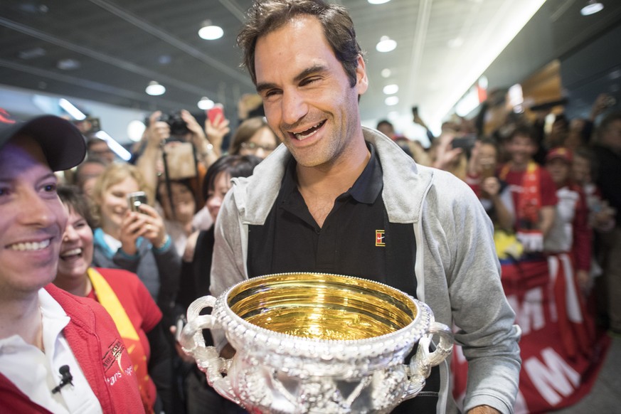 Swiss tennis player Roger Federer carries the Australian Open trophy and greets fans during his arrival at Zurich Airport, in Kloten, Switzerland, 30 January 2018. Federer won the men&#039;s singles f ...