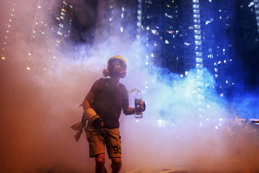 A protester stands in the midst of tear gas during confrontation with police in Hong Kong during the early hours of Sunday, Aug. 4, 2019. Hong Kong protesters ignored police warnings and streamed past ...
