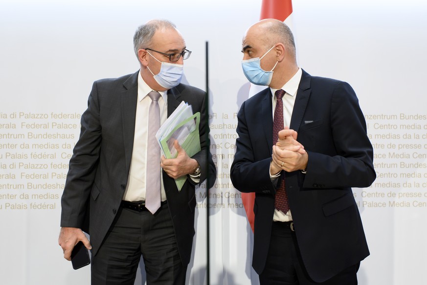 Bundespraesident Guy Parmelin, links, und Bundesrat Alain Berset, rechts, sprechen nach einer Medienkonferenz zur Lieferung von Impfdosen und die laufende Impfkampagne, am Donnerstag, 25. Maerz 2021 i ...