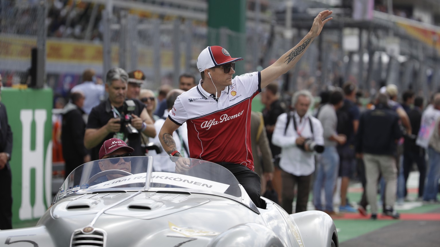 Alfa Romeo driver Kimi Raikkonen of Finland waves as sits at an old Alfa Romeo car during the drivers parade prior to the Formula One Italy Grand Prix at the Monza racetrack, in Monza, Italy, Sunday,  ...