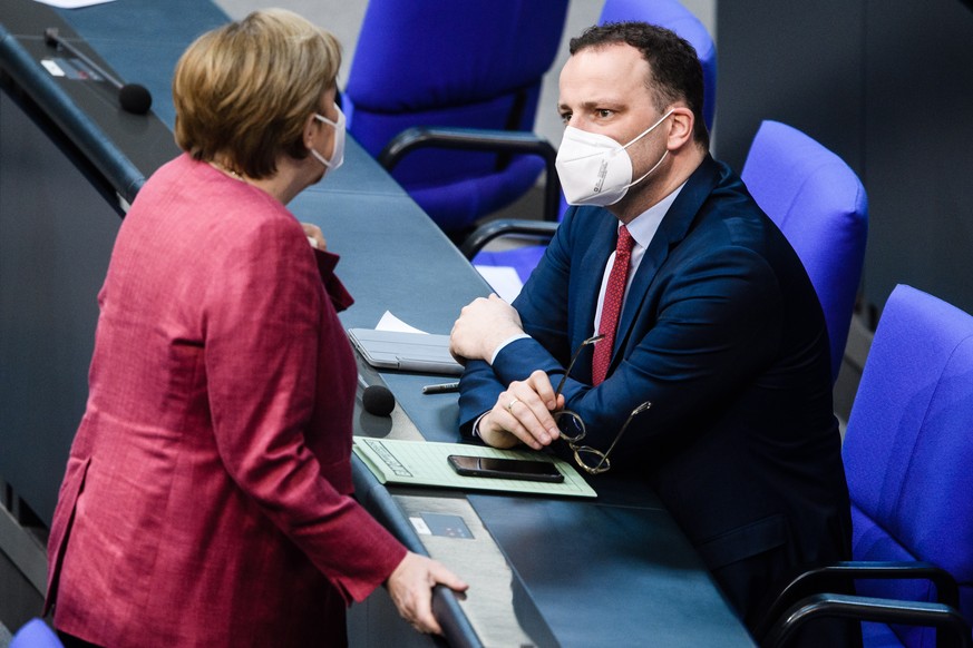 epa09138829 German Chancellor Angela Merkel (L) and German Health Minister Jens Spahn wear face masks as they talk during a session of the German parliament Bundestag in Berlin, Germany, 16 April 2021 ...