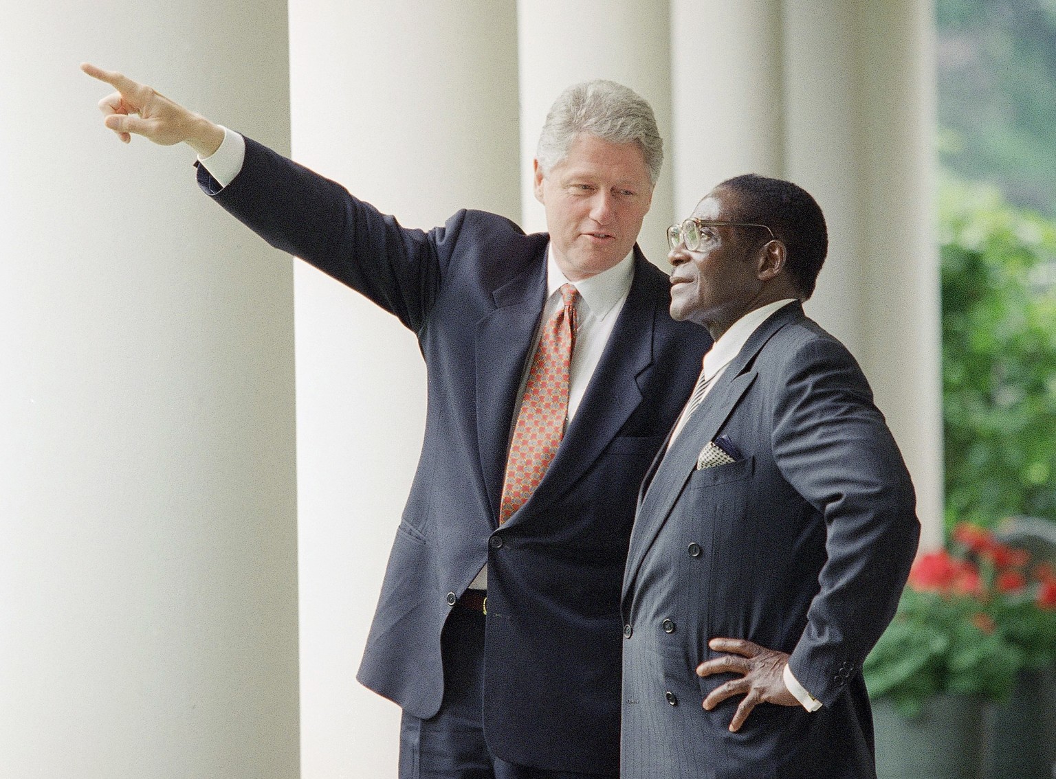 FILE - In this May 18, 1995 file photo President Bill Clinton gestures while talking to Zimbabwe Prime Minister Robert Mugabe in the Colonnades of the White House, Washington after their Oval Office m ...
