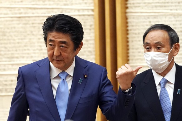 FILE - In this May 4, 2020, file photo, then Japan&#039;s Prime Minister Shinzo Abe, left, gestures by then Chief Cabinet Secretary Yoshihide Suga at the end of a news conference at the prime minister ...