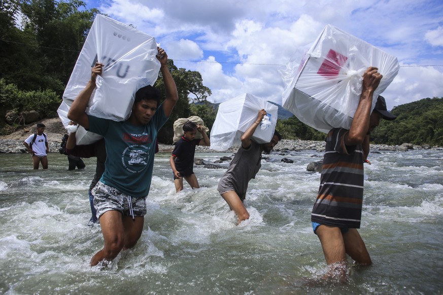 epa07535650 Indonesian election workers carry ballot boxes as they cross a river to deliver the electoral logistics to remote villages in Maros, South Sulawesi, Indonesia, 16 April 2019 (issued 29 Apr ...