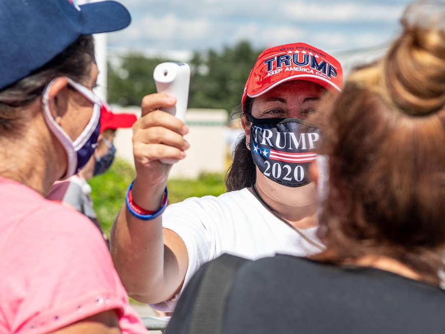 October 12, 2020 - Sanford, FL, U.S: A volunteer checks temperatures before entry to the Republican presidential nominee Donald Trump rally at Orlando Sanford International Airport Million Air Hanger  ...