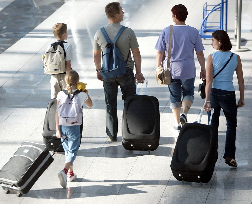 Eine Familie zieht am 31. Juli 2003 am Flughafen in Duesseldorf ihre Koffer in Richtung Urlaub. Rollkoffer koennen hohe Mengen an Schadstoffen enthalten und auf Reisen schnell kaputt gehen, wie das Ve ...