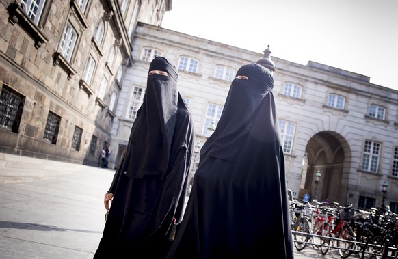 epa06775145 Women wearing the niqab walk in front of the Danish Parliament at Christiansborg Castle in Copenhagen, Denmark, 31 May 2018. A majority in the Danish Parliament adopted a ban wearing niqab ...