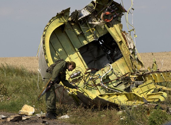 FILE - In this July 22, 2014 file photo, a pro-Russian rebel touches the MH17 wreckage at the crash site of Malaysia Airlines Flight 17, near the village of Hrabove, eastern Ukraine. Three Russians an ...