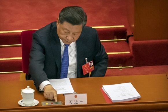 President Xi Jinping reaches out to vote on a piece of national security legislation concerning Hong Kong during the closing session of China&#039;s National People&#039;s Congress (NPC) in Beijing, W ...