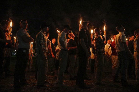 FILE - In this Aug. 11, 2017, file photo, multiple white nationalist groups march with torches through the University of Virginia campus in Charlottesville, Va. A federal judge has issued an arrest wa ...