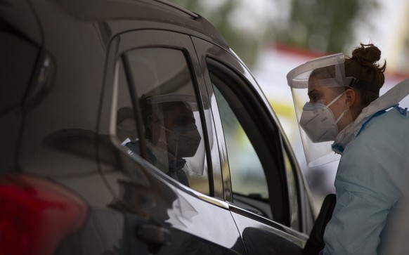A health care worker speaks with a man in a car as she prepares to administer a nose-swab test at the mobile COVID-19 testing site in Antwerp, Belgium, Tuesday, Oct. 20, 2020. Bars and restaurants acr ...