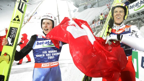 Switzerland&#039;s gold medal winner Andreas Kuettel, right, and his compatriot Simon Ammann celebrate with the Swiss flag after the 2dn round was canceled during the Men&#039;s Large Hill Individual  ...