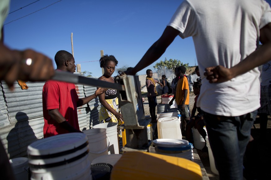 In this June 23, 2015 photo, people wait in line to fill buckets with water at a pump in Canaan, Haiti. Residents say this pump, like most of those in Canaan, produces water that is too salty to drink ...