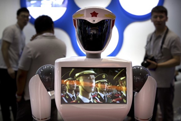 A video screen plays footage of Chinese People&#039;s Liberation Army (PLA) soldiers on a robot from Chinese robot maker Jiangsu Eastern Golden Jade Intelligent Robot Co. at the World Robot Conference ...