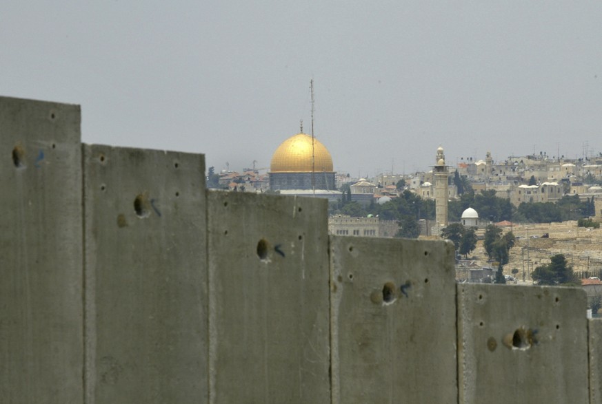 FILE - This July 9, 2004 file photo shows the golden shrine of the Dome of the Rock in Jerusalem&#039;s Old city can be seen behind a section made of concrete walls of the controversial separation bar ...