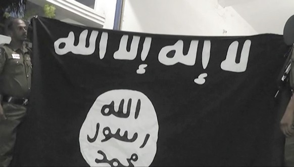In this Friday, April 26, 2019, image made from video, officers hold up an Islamic State group flag in Arabic that reads: &quot;There is no God, but Allah&quot; and &quot;Allah, Prophet, Muhammad&quot ...