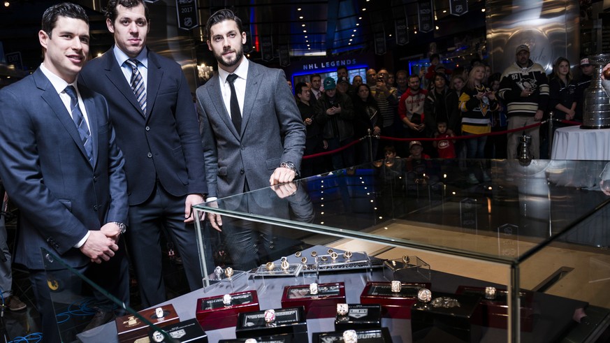 Pittsburgh Penguins&#039; Sidney Crosby, Evgeni Malkin and Chris Letang, from left, gather for a photo next to a display case holding the 2017 NHL hockey Stanley Cup champions&#039; ring that was dona ...