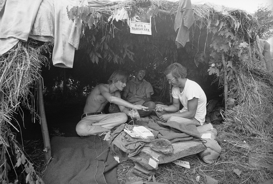 FILE - This Aug. 17, 1969 file photo shows music fans seeking shelter is a grass hut at the Woodstock Music and Art Festival in Bethel, N.Y. where the sign above reads &quot;Have a Marijuana.&quot; Wo ...