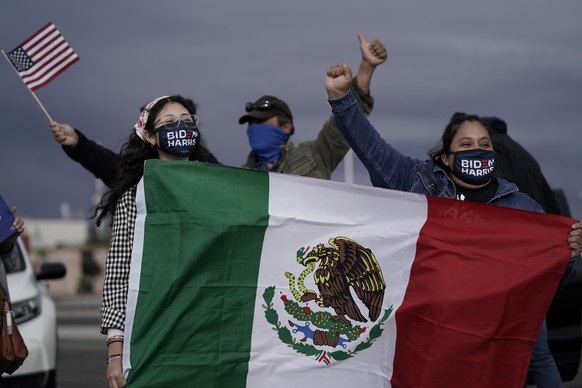 Supporters of President-elect Joe Biden and Vice President-elect Kamala Harris hold up a flag of Mexico while cheering at a news conference before a car caravan in Las Vegas, Saturday, Nov. 7, 2020. B ...