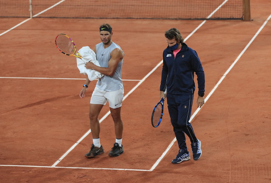 Spain&#039;s Rafael Nadal, left, and his coach Francisco Roig wearing a face mask to prevent the spread of coronavirus walk on the clay during practicing at the Roland Garros stadium in Paris, Friday, ...