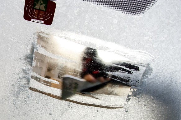 A person takes off ice on his car windscreen, in Geneva, Switzerland, Monday, December 22, 2014. (KEYSTONE/Salvatore Di Nolfi)