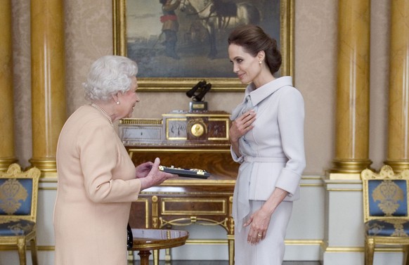 U.S actress Angelina Jolie, right, is presented with the Insignia of an Honorary Dame Grand Cross of the Most Distinguished Order of St Michael and St George by Britain&#039;s Queen Elizabeth II at Bu ...
