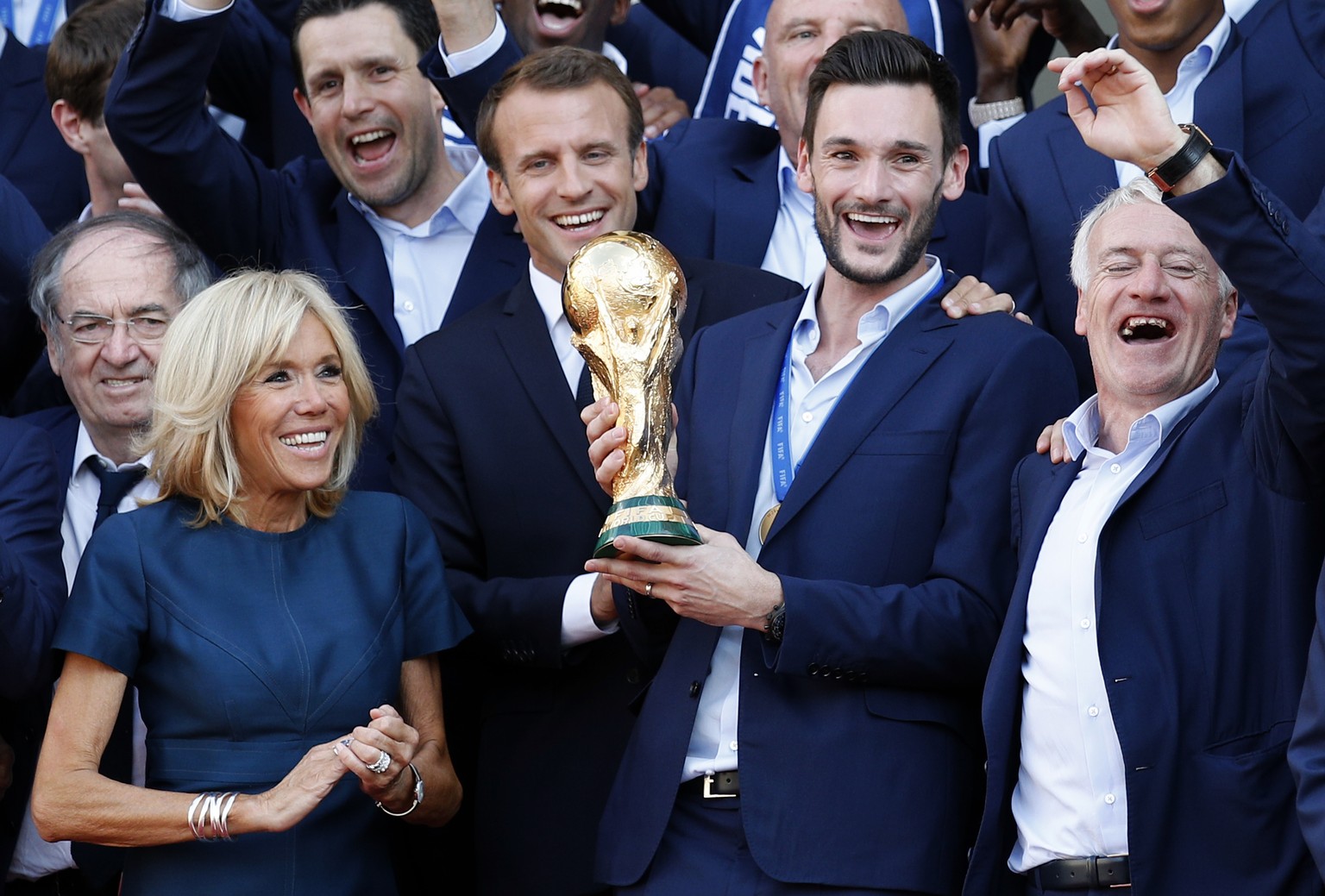 French President Emmanuel Macron, second left, his wife Brigitte, team captain Hugo Lloris holding the cup, while head coach Didier Deschamps, right, gestures at the presidential Elysee Palace after t ...
