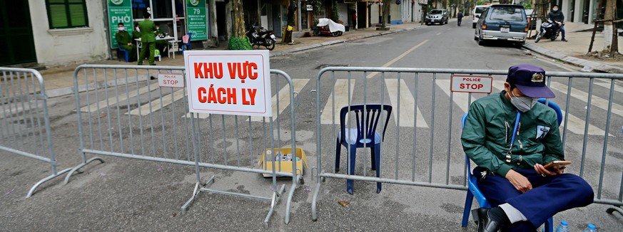 epa08275847 A security man sits in front of a barrier with a sign reading &#039;Isolation Region&#039; on Truc Bach street in Hanoi, Vietnam, 07 March 2020. A 26-year-old Vietnamese woman recently bac ...