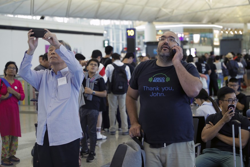 Travelers check the outbound flights information at the Hong Kong International Airport, Monday, Aug. 12, 2019. One of the world&#039;s busiest airports cancelled all remaining flights for the day aft ...